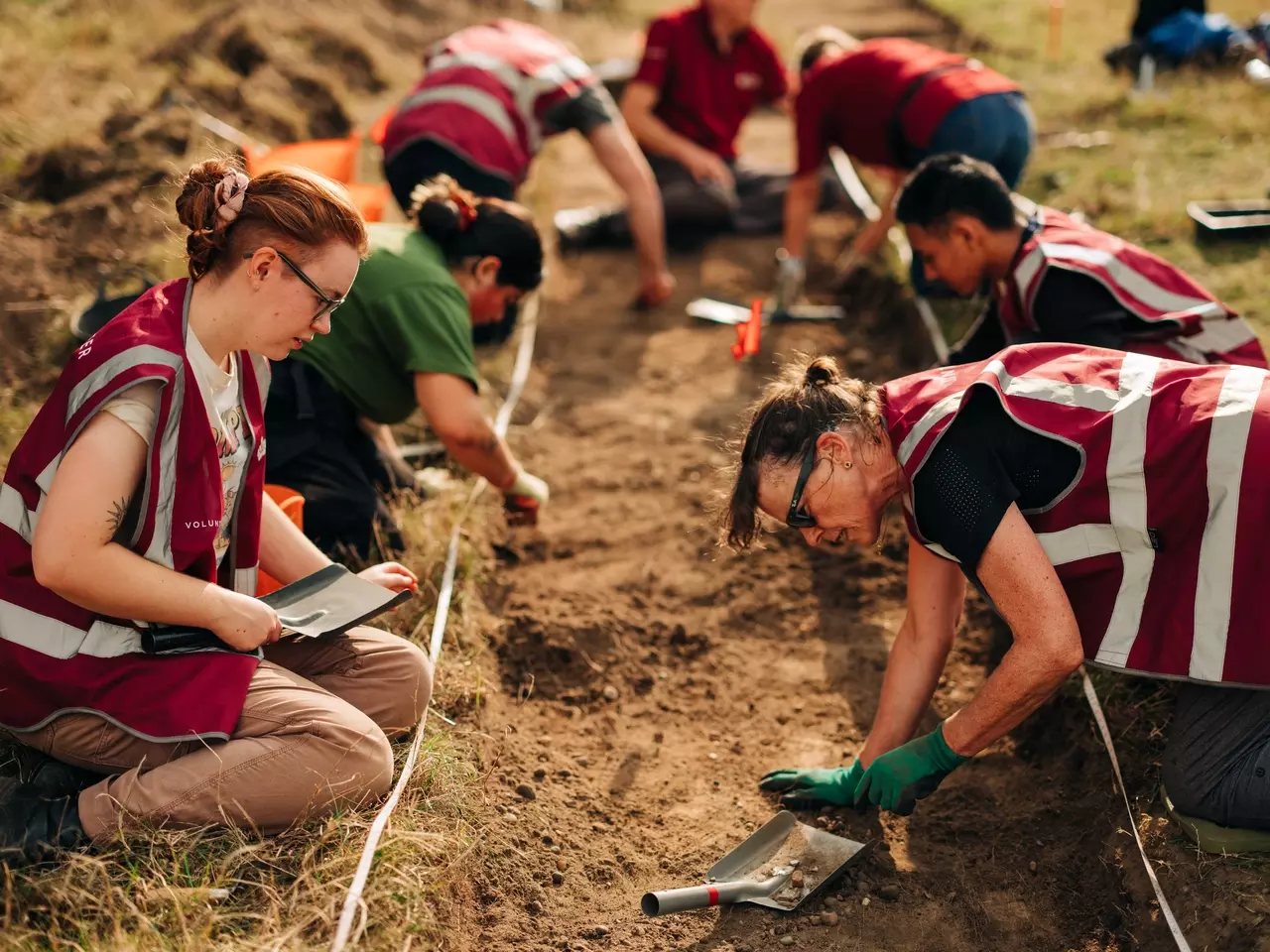 A close up on volunteers digging on the Grand Ascent in the sunshine.