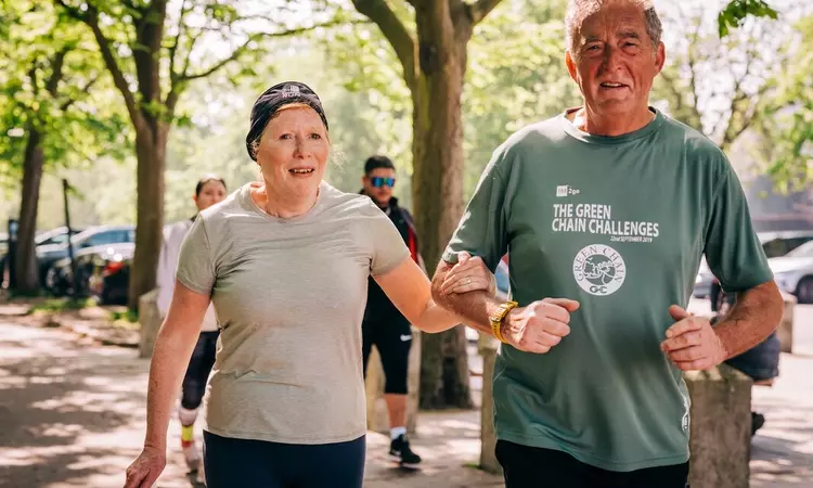 An older man and woman in running clothes linking arms